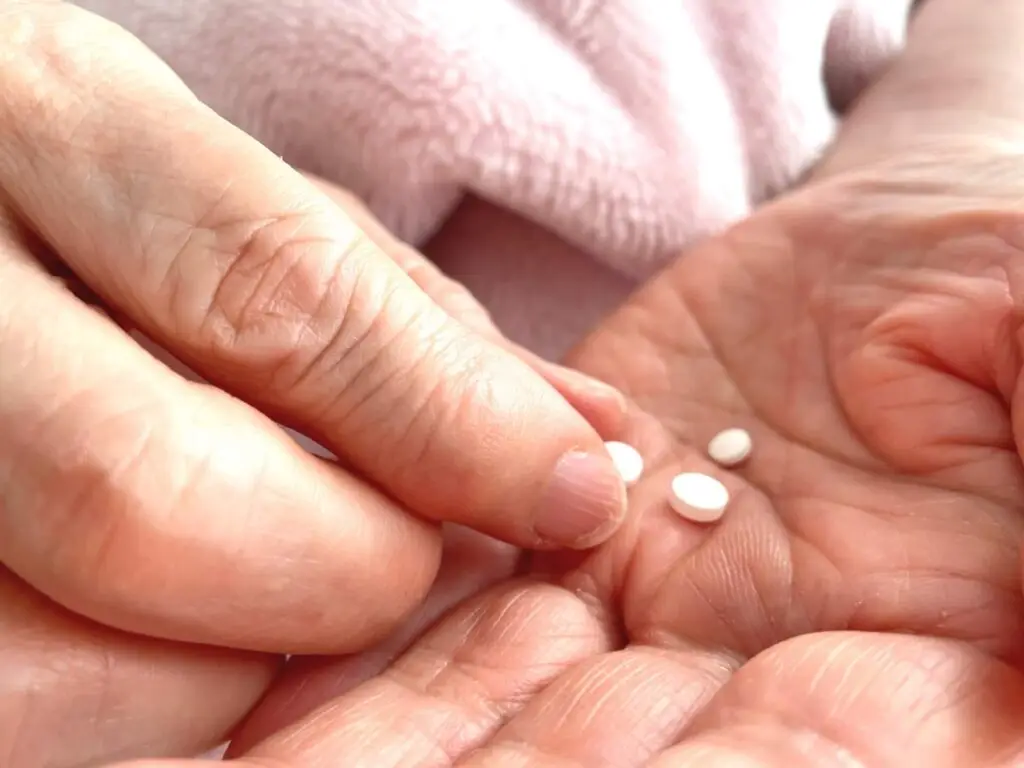 老人手中拿著藥丸，象徵胃藥與骨質疏鬆之間的潛在風險